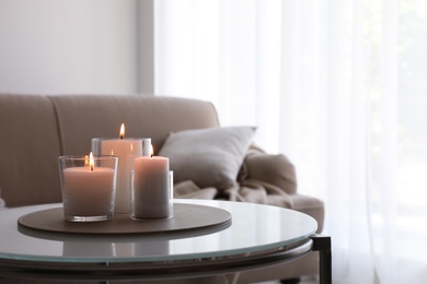 Photo of Burning candles in glass holders on table indoors. Space for text