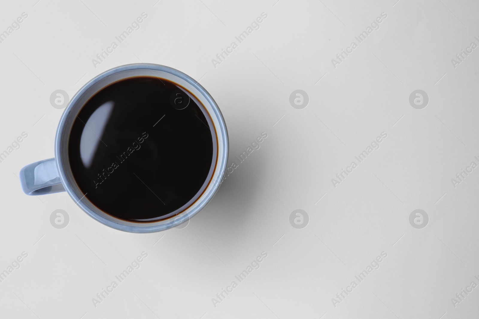 Photo of Mug of freshly brewed hot coffee on white background, top view. Space for text