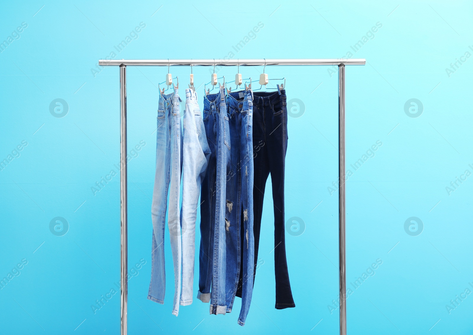 Photo of Rack with stylish jeans on color background