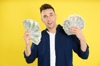 Emotional man with cash money on yellow background