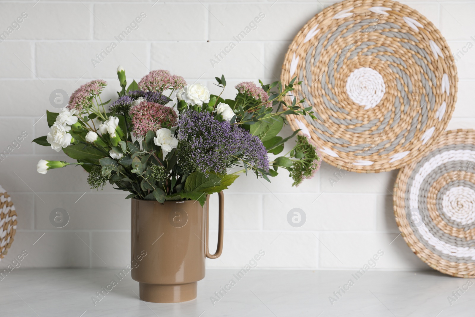 Photo of Ceramic vase with beautiful bouquet on light table near white brick wall