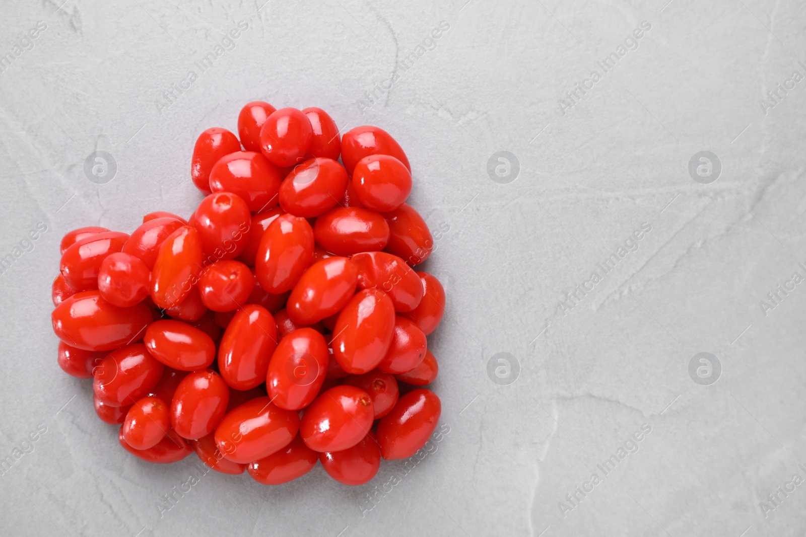 Photo of Heart made of fresh goji berries on grey background, top view. Space for text