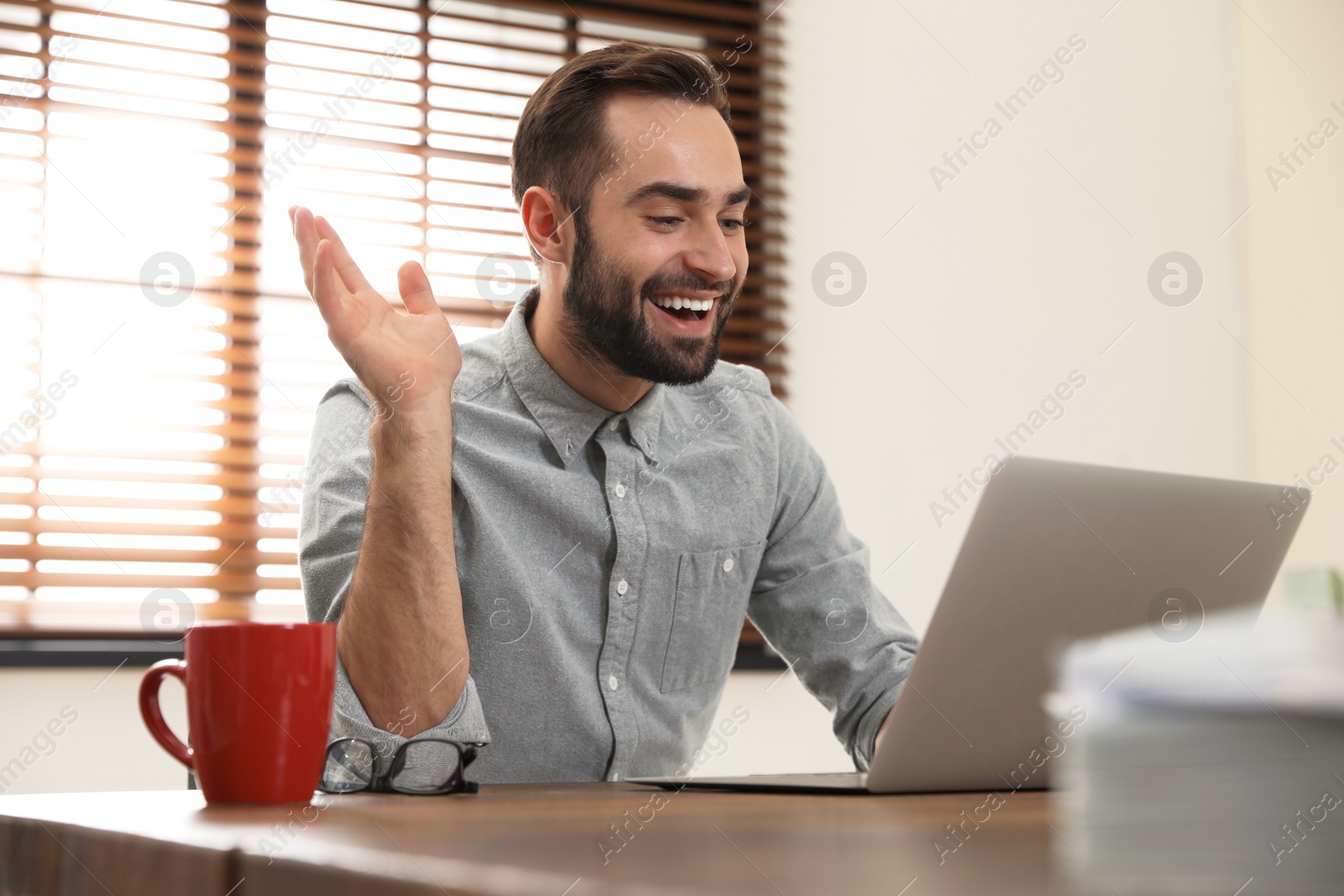 Photo of Man using video chat on laptop in home office