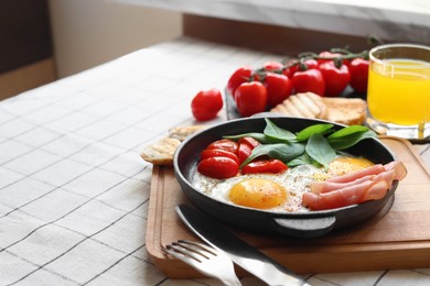 Photo of Delicious fried eggs with spinach, tomatoes and ham served on table. Space for text