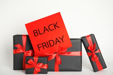Many gift boxes and sheet of paper with words Black Friday on white background