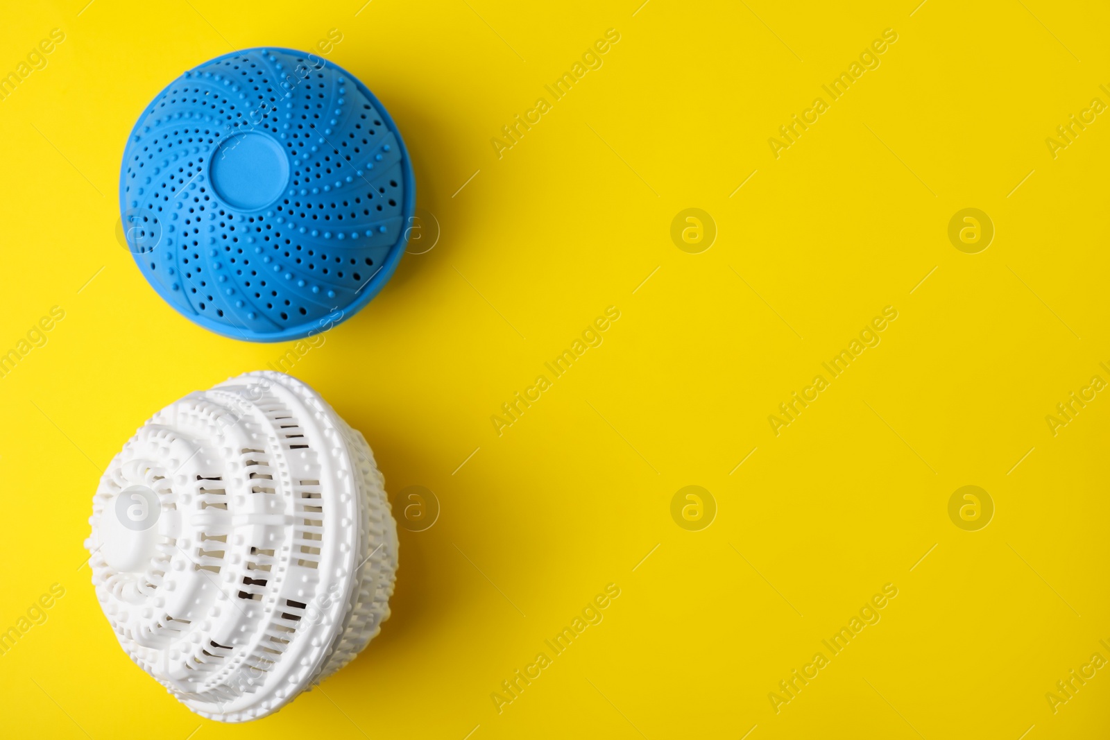 Photo of Laundry dryer balls on yellow background, flat lay. Space for text