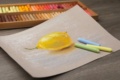 Beautiful drawing of lemon and pastels on wooden table, closeup