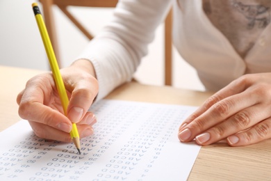 Student filling answer sheet at table, closeup