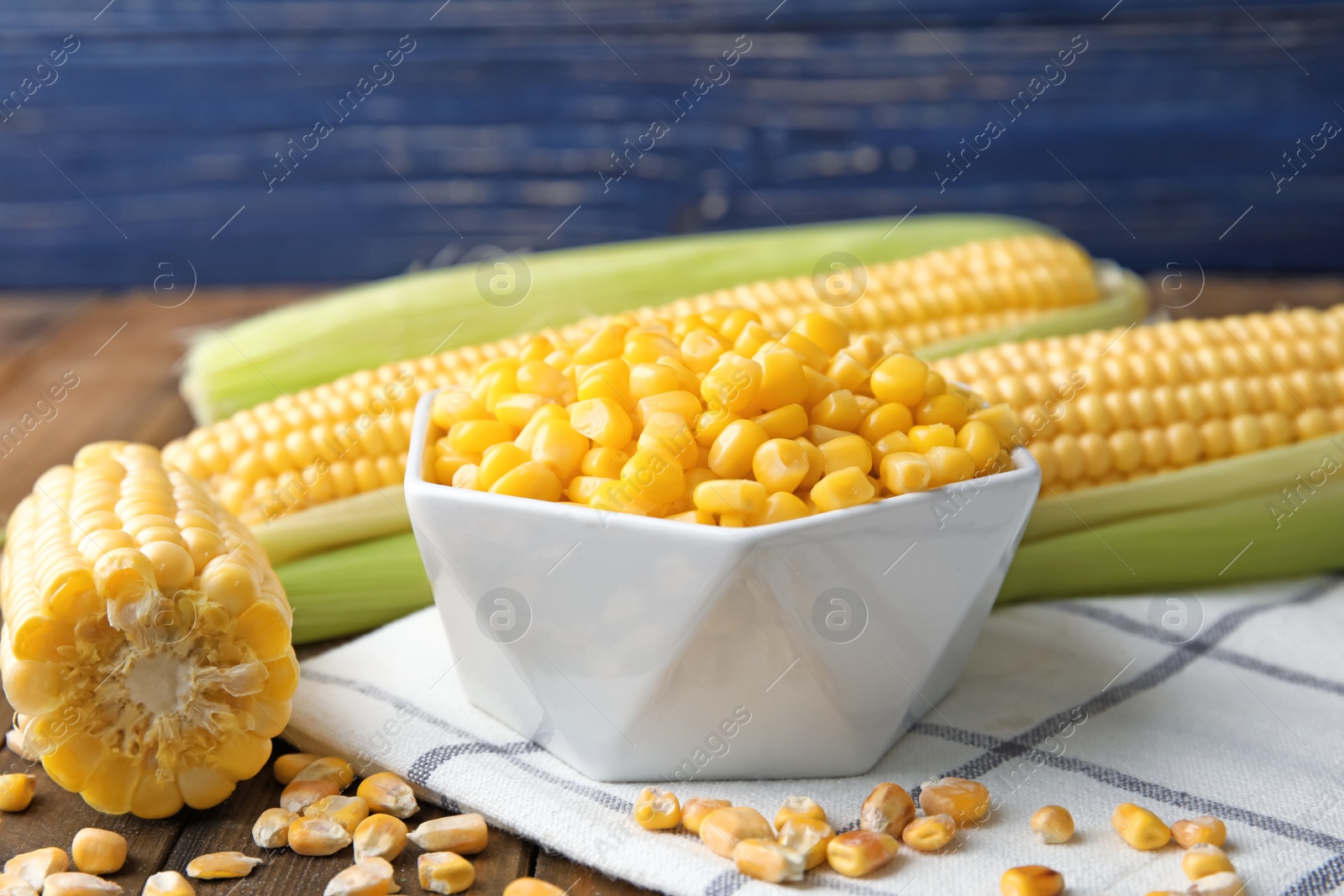 Photo of Bowl with corn kernels and cobs on wooden table