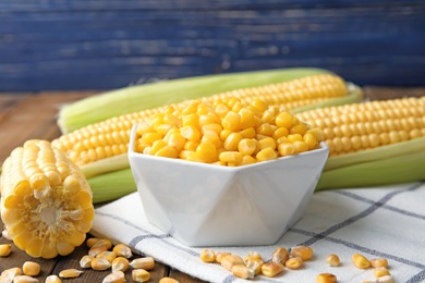 Bowl with corn kernels and cobs on wooden table