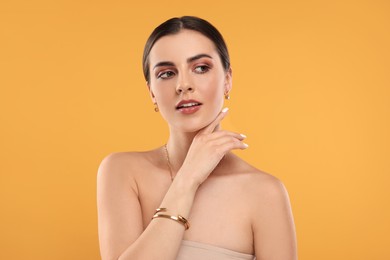 Beautiful woman with elegant jewelry on orange background