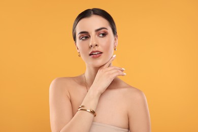 Photo of Beautiful woman with elegant jewelry on orange background