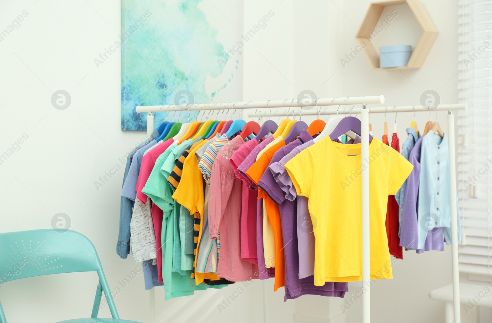 Photo of Different child's clothes hanging on racks in room