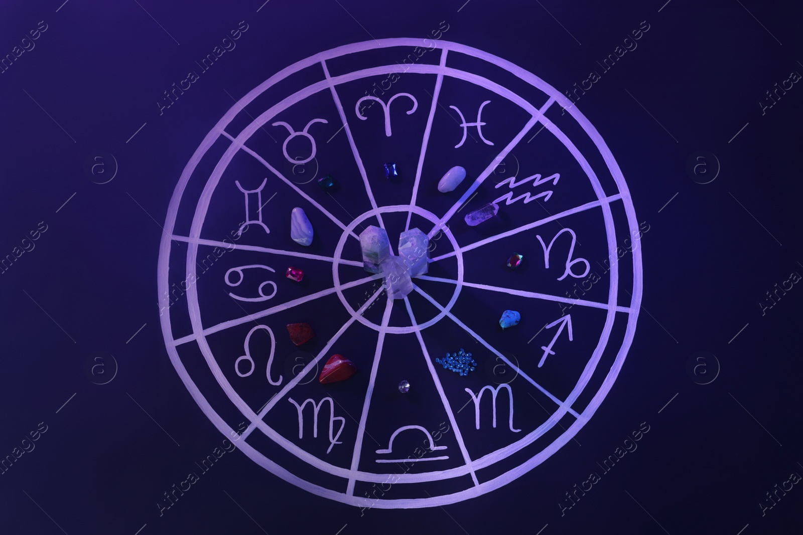 Photo of Natural stones for zodiac signs and drawn astrology chart on dark blue background, flat lay. Color tone effect