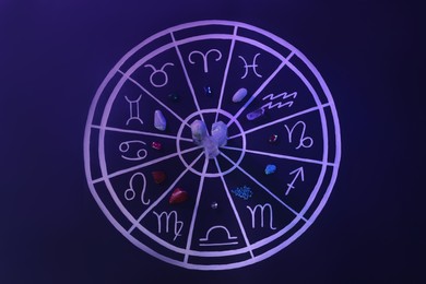 Photo of Natural stones for zodiac signs and drawn astrology chart on dark blue background, flat lay. Color tone effect