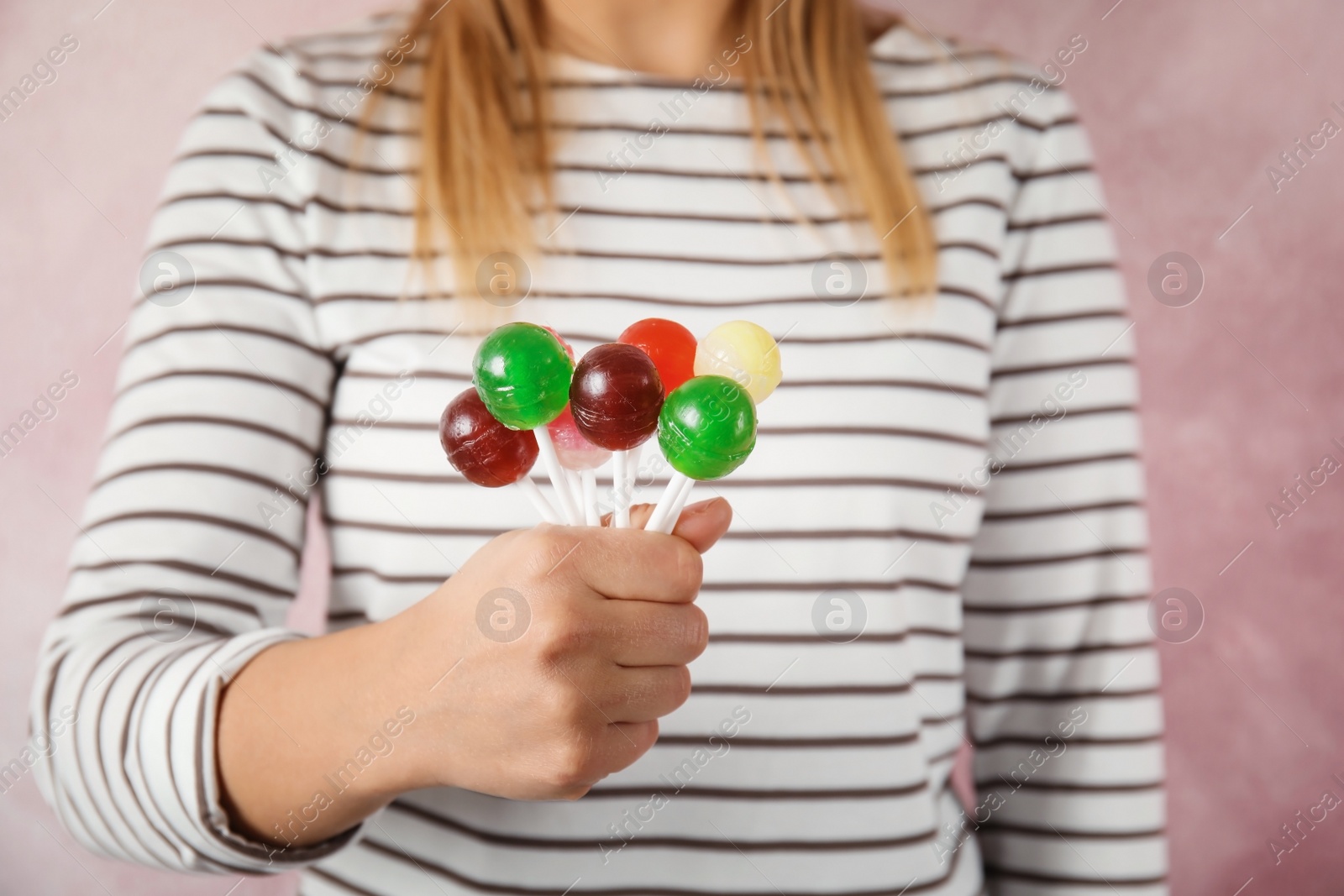 Photo of Woman holding many colorful lollipop candies on color background, closeup