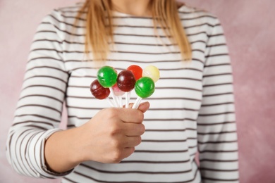 Woman holding many colorful lollipop candies on color background, closeup