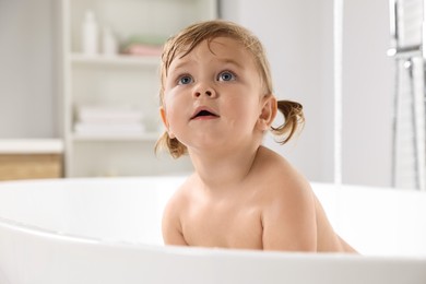 Photo of Cute little girl in bathtub at home