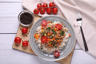Photo of Tasty dish with fried minced meat, rice, carrot, tomatoes and corn served on white wooden table, flat lay