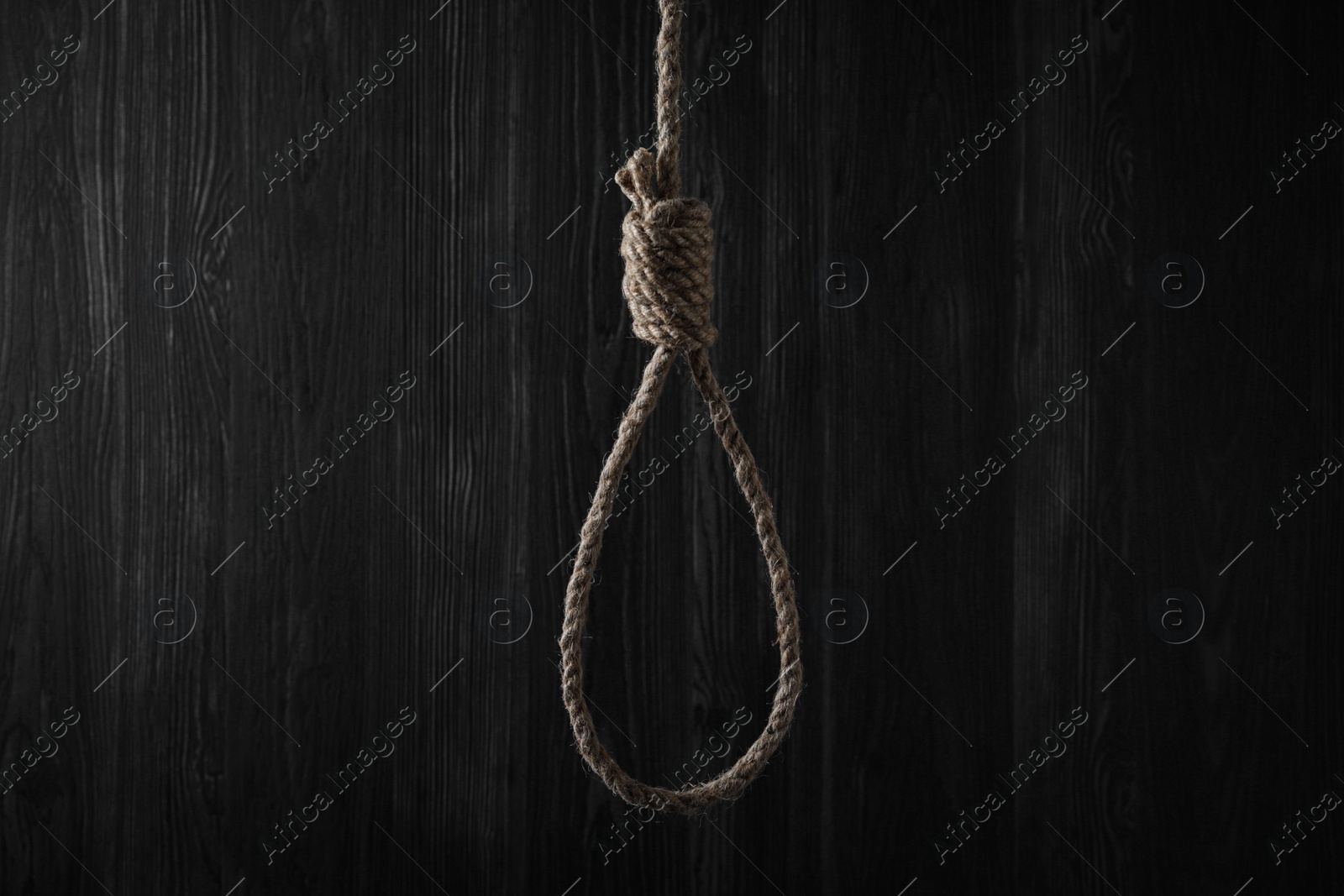 Photo of Tied rope noose against dark wooden background