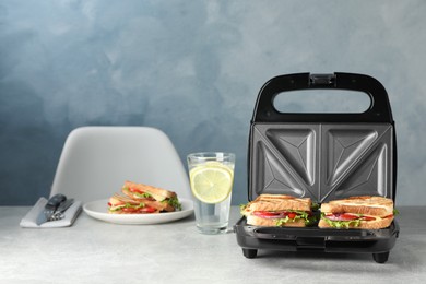 Photo of Modern grill maker with sandwiches and breakfast served on grey table
