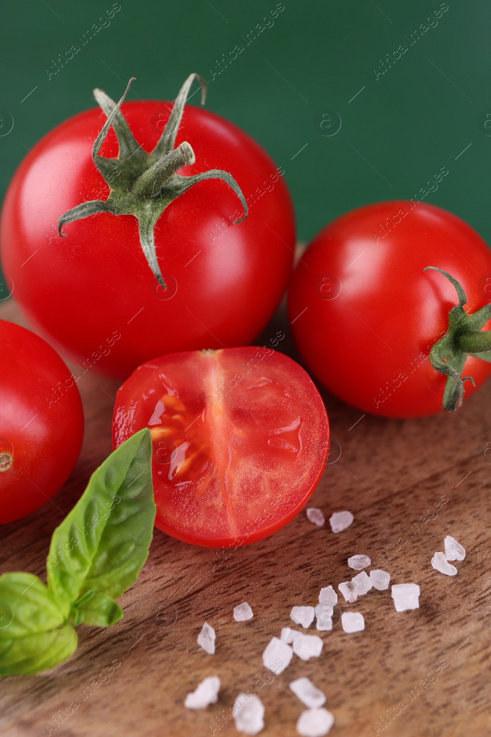 Photo of Whole and cut tomatoes on wooden board, closeup