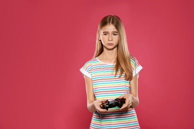 Photo of Teenage girl playing video games with controller on color background
