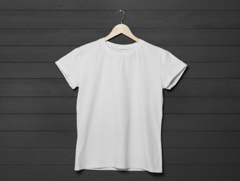 Hanger with stylish white T-shirt on gray wooden wall