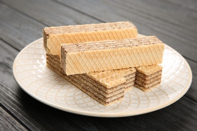 Photo of Plate with delicious crispy wafers on wooden table