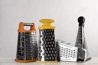 Different modern graters on white wooden table