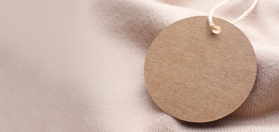 Blank tag on beige fabric, closeup view with space for text. Banner design