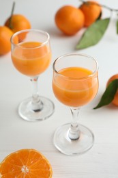 Photo of Tasty tangerine liqueur in glasses and fresh citrus fruits on white table