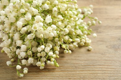 Photo of Beautiful lily of the valley bouquet on wooden table, closeup. Space for text