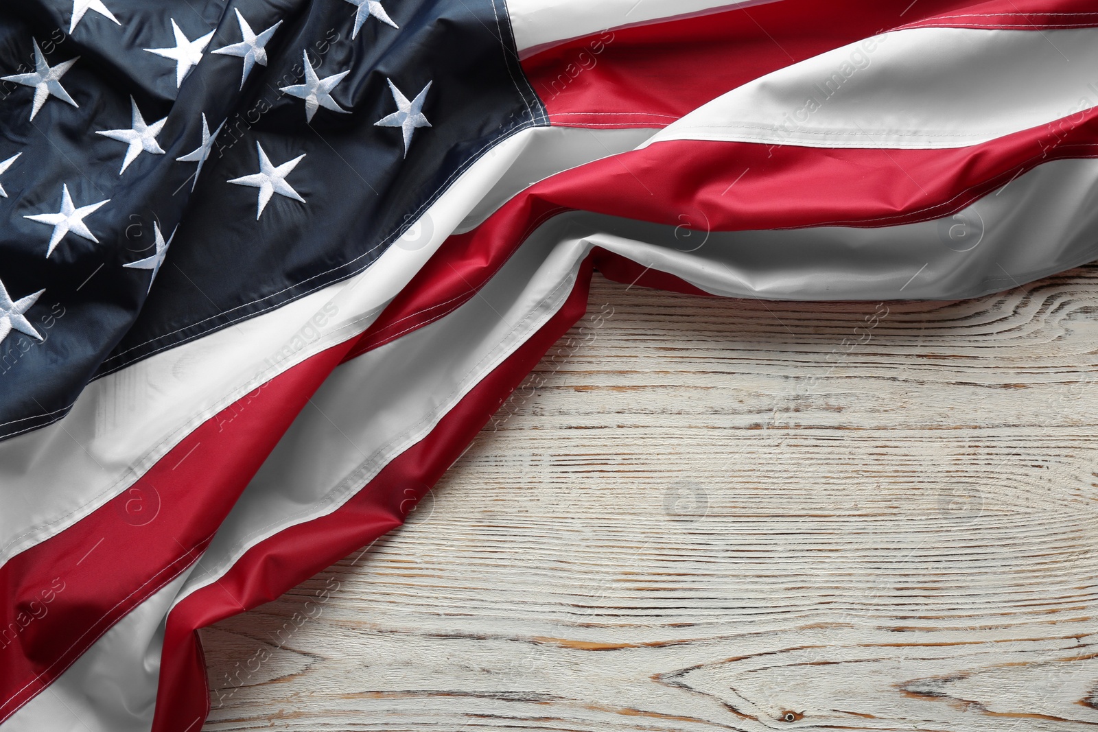 Photo of American flag on white wooden background, top view with space for text