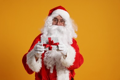 Photo of Santa Claus holding Christmas gift on orange background