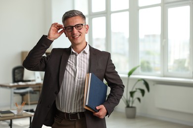 Photo of Happy man with notebooks in office, space for text