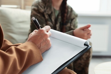 Psychologist working with military officer in office, focus on hand