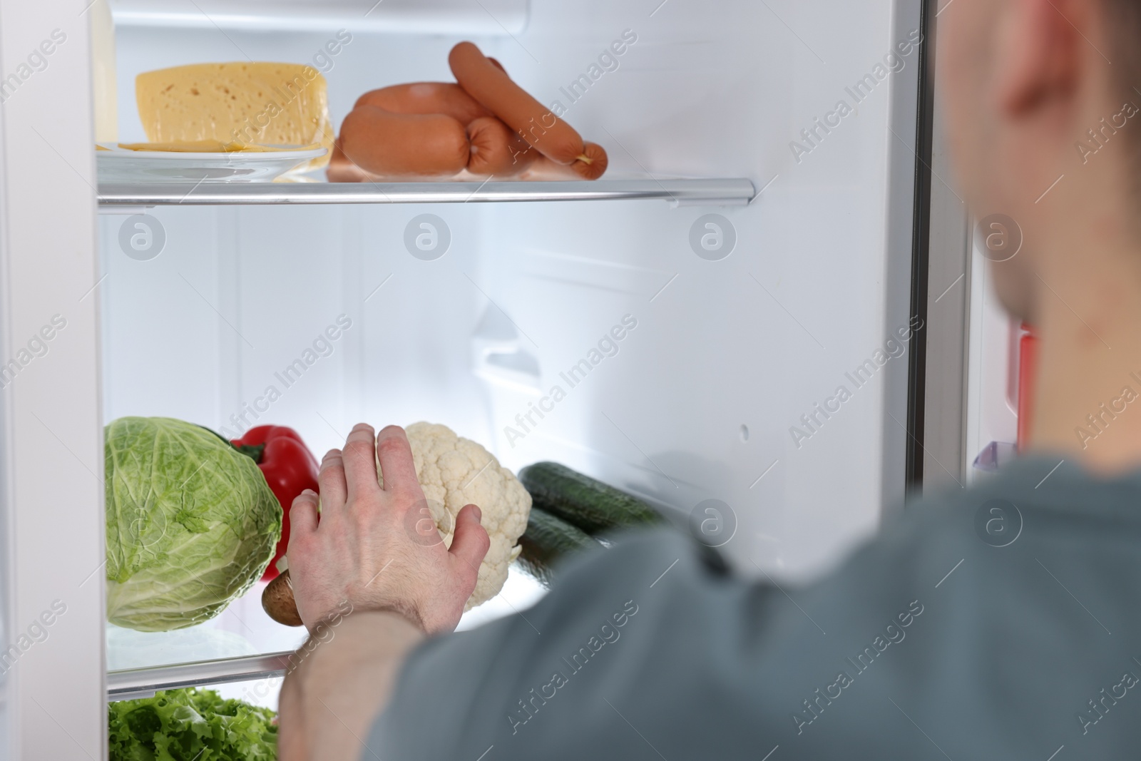 Photo of Man taking cauliflower out of refrigerator, closeup