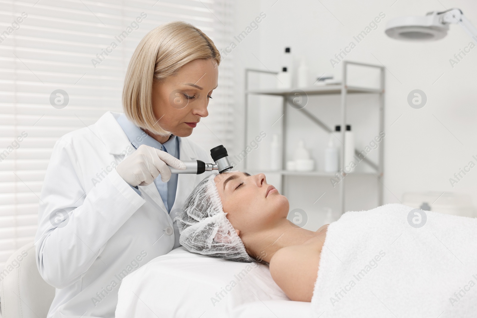 Photo of Dermatologist with dermatoscope examining patient`s face in clinic