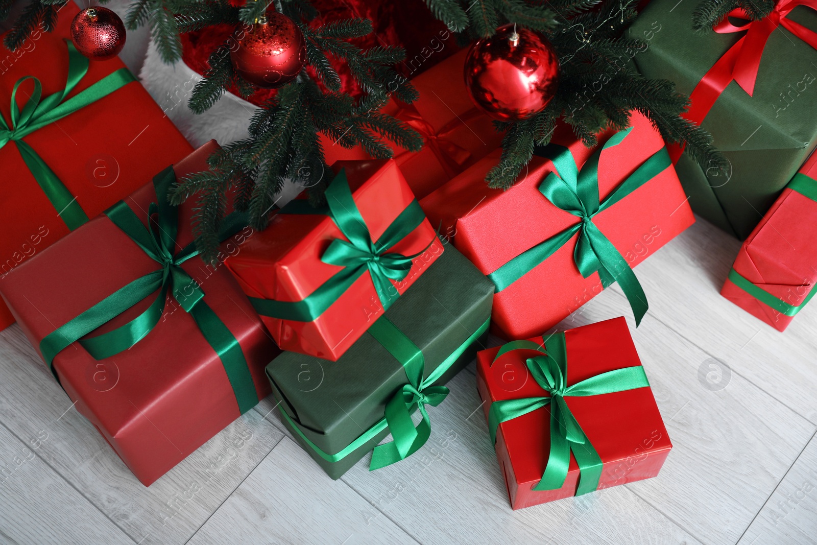 Photo of Beautifully wrapped gift boxes under Christmas tree indoors, above view