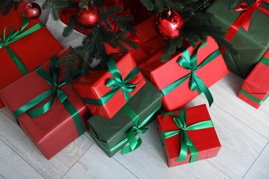 Beautifully wrapped gift boxes under Christmas tree indoors, above view