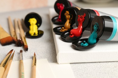 Photo of Tubes of colorful paints and brushes on textured table, closeup