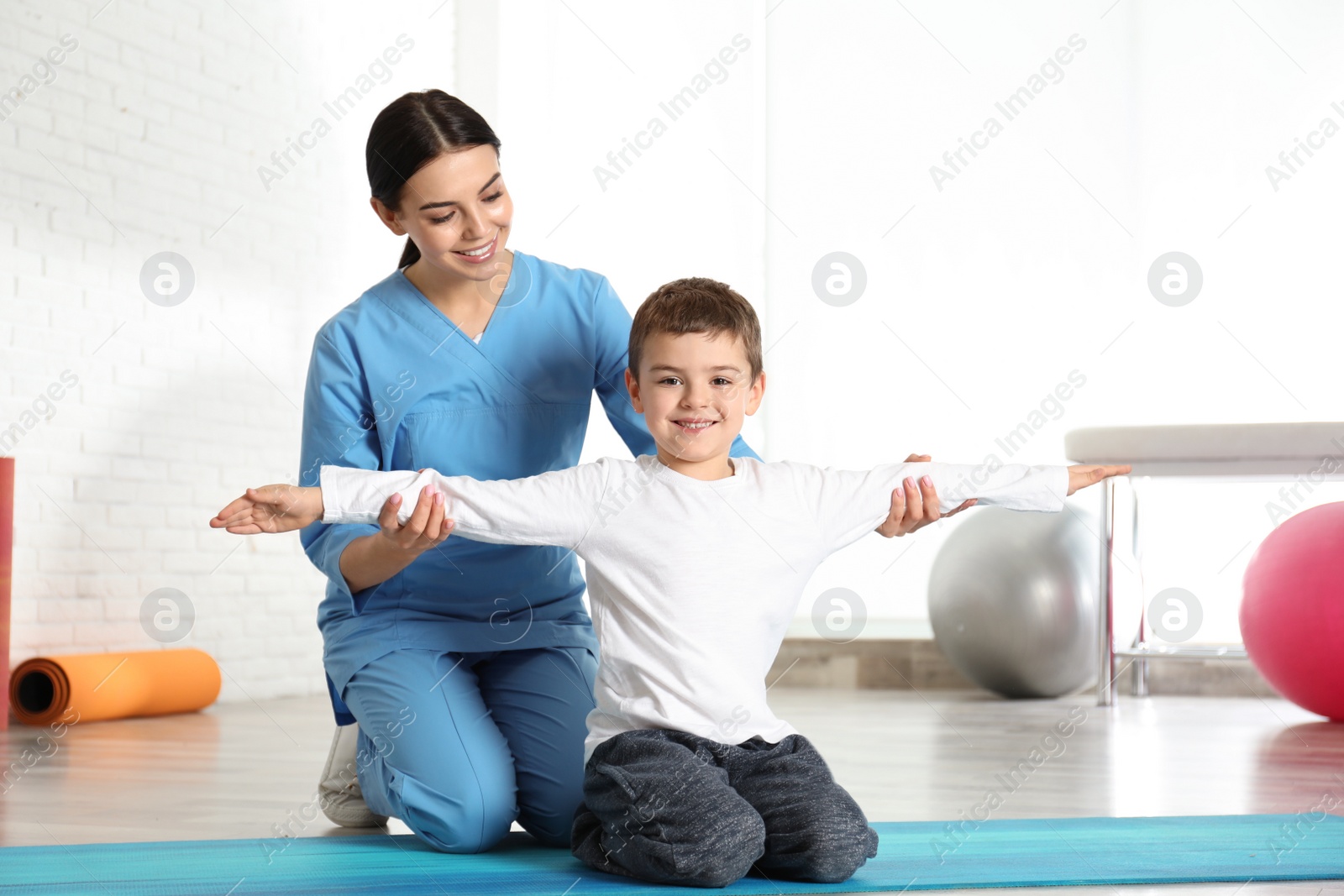 Photo of Orthopedist working with little boy in hospital gym