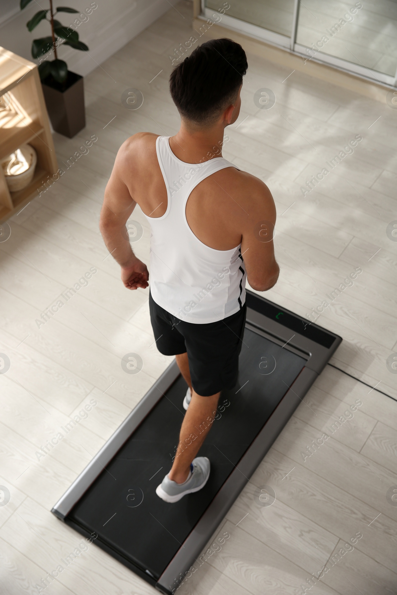 Photo of Sporty man training on walking treadmill at home