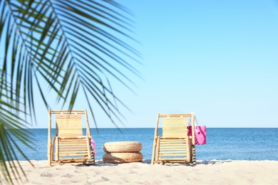 Wooden sunbeds and beach accessories on sandy shore