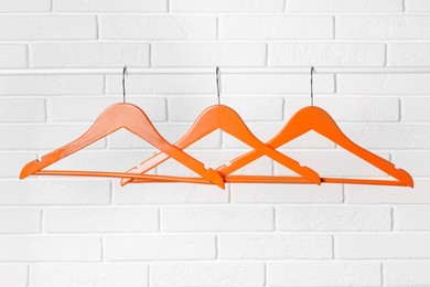 Photo of Orange clothes hangers on rail near white brick wall