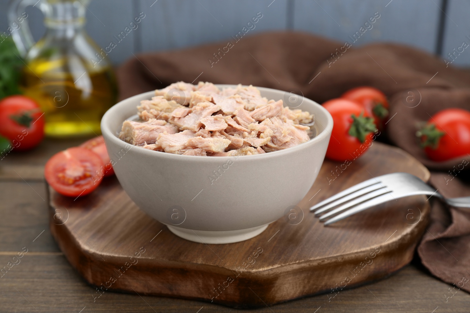 Photo of Bowl with canned tuna on wooden table