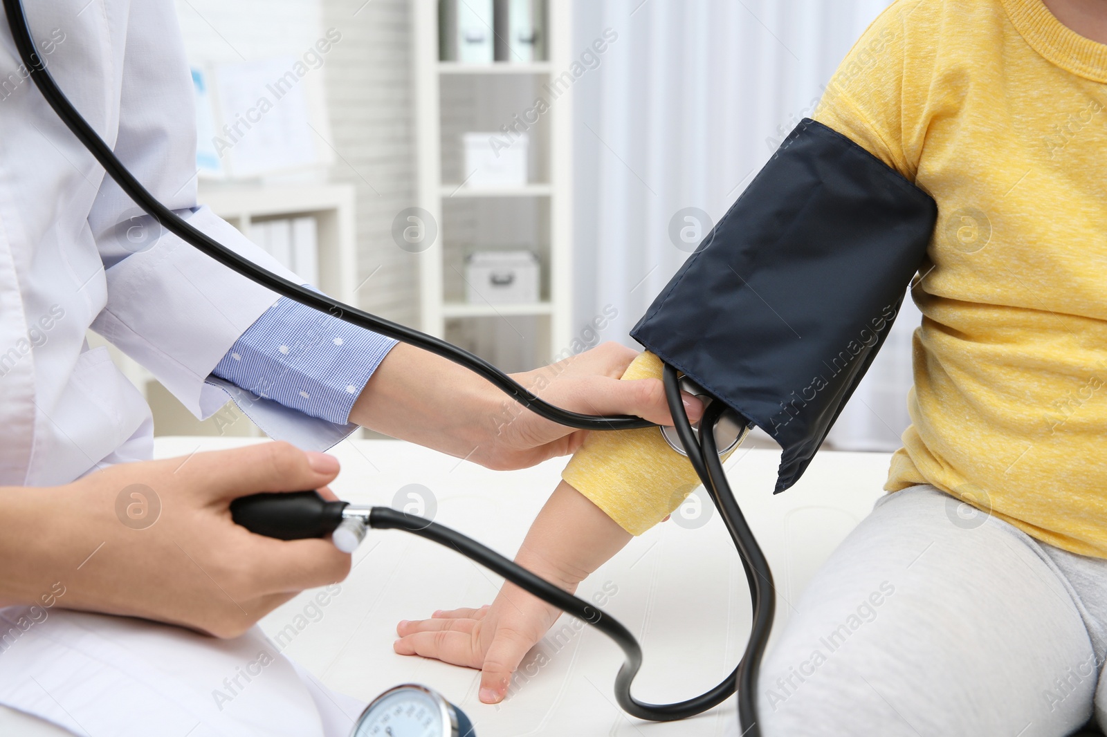 Photo of Little girl visiting doctor in hospital, closeup. Measuring blood pressure and checking pulse