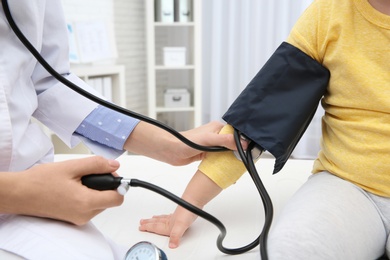 Little girl visiting doctor in hospital, closeup. Measuring blood pressure and checking pulse