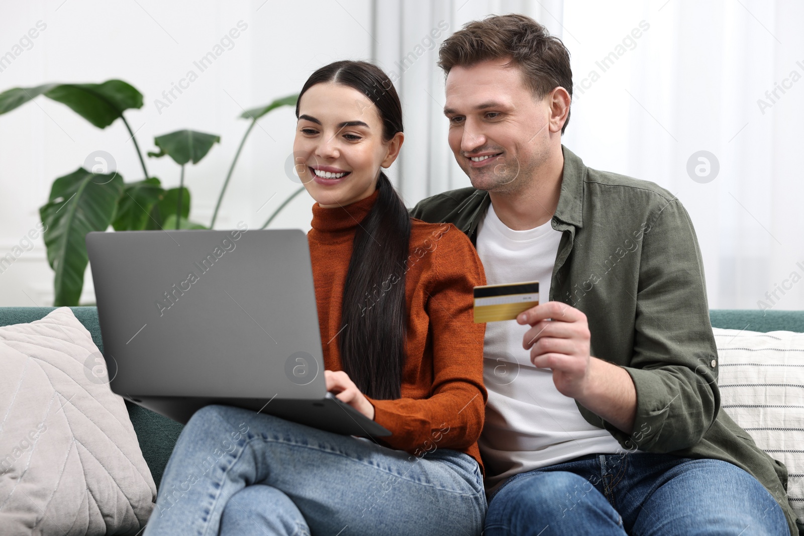 Photo of Happy couple with laptop and credit card shopping online together at home